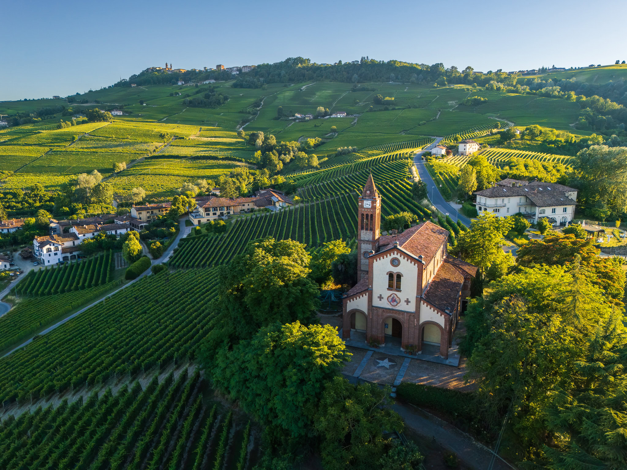 Veduta aerea chiesa con vigneti delle Langhe, La Morra sullo sfondo, territorio del Barolo, Piemonte