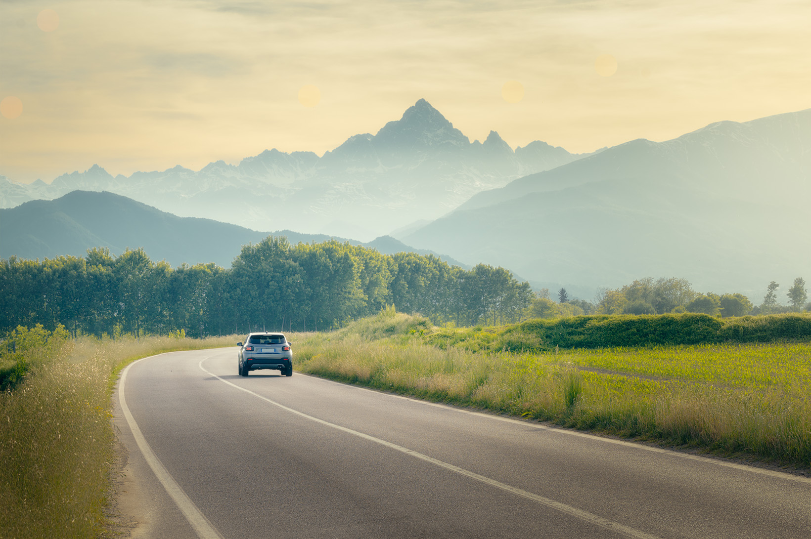 Auto sulla strada verso la montagna al tramonto