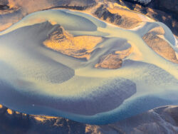 Texture astratta di fiumi glaciali che si intrecciano su sedimenti lavici, ripresa aerea zenitale di fotografia di territorio d'autore