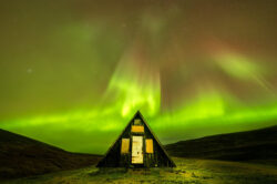Aurora boreale verde e rossa sopra una tradizionale capanna di legno islandese, astrofotografia di paesaggio di Carlo Pagliuca