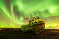 Antico relitto di barca da pesca sulla spiaggia islandese sotto una spettacolare aurora boreale, fotografia notturna di Carlo Pagliuca