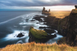 Faraglioni basaltici Lóndrangar sulla costa islandese illuminati dalla luce calda del tramonto, fotografia di paesaggio di Carlo Pagliuca